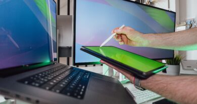 A person using a stylus on a tablet in a tech-savvy workspace with dual monitors